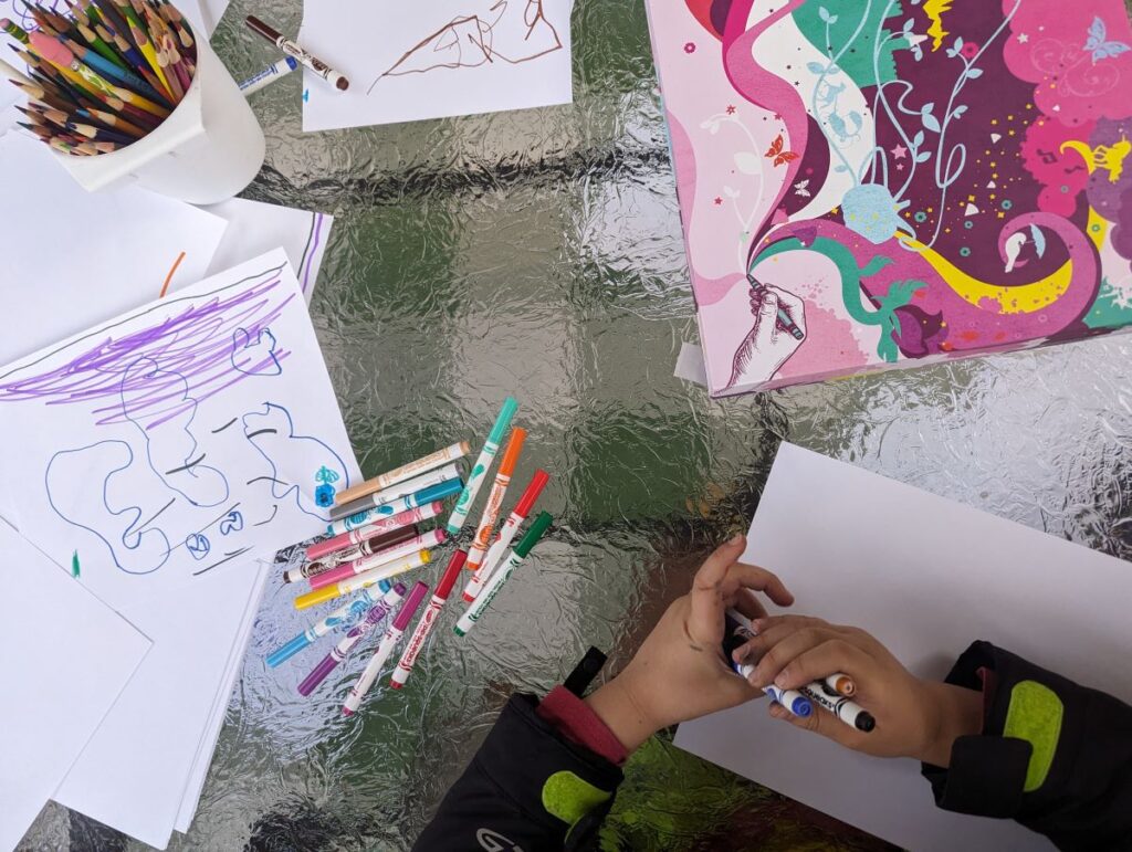 Child using markers and art supplies on a table for homeschool