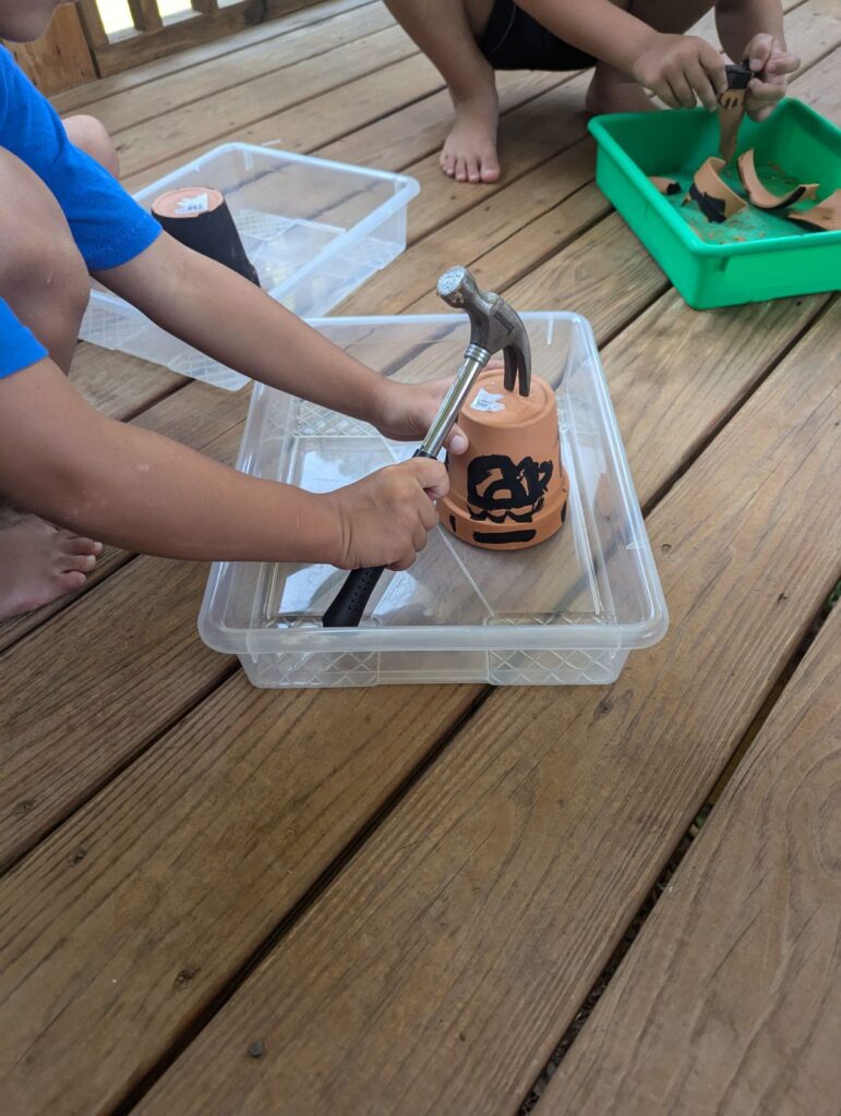 child using a hammer to break clay pot
